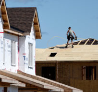Builders work on the roof of a home in a new subdivision in the Ottawa suburb of Kanata, on Friday, July 30, 2021. Justin Tang/The Canadian Press. 