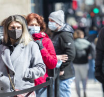 People wear face masks as they wait to enter a store in Montreal, Friday, April 2, 2021. Graham Hughes/The Canadian Press.