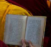 Exile Tibetan Buddhist monks share a text as they listen to their spiritual leader the Dalai Lama deliver a religious talk at the Tsuglakhang temple in Dharmsala, India, Friday, March 18, 2022. Ashwini Bhatia/AP Photo.