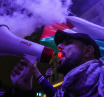 A man uses a bullhorn as smoke bombs are set off during a demonstration in support of Palestine, in Vancouver, on Thursday, October 19, 2023. Darryl Dyck/The Canadian Press. 