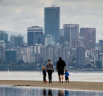 A family walks along a sandbar between tidal pools off Spanish Banks Beach as the tide comes in, in Vancouver B.C., on Monday May 20, 2013. Darryl Dyck/The Canadian Press. 